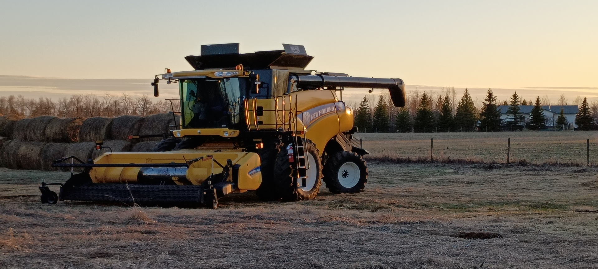 New Holland combine harvester at sunset on the prairies